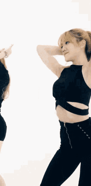 a woman wearing a black crop top and black pants is dancing