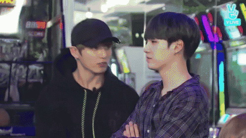 two young men are standing next to each other in an arcade and talking .