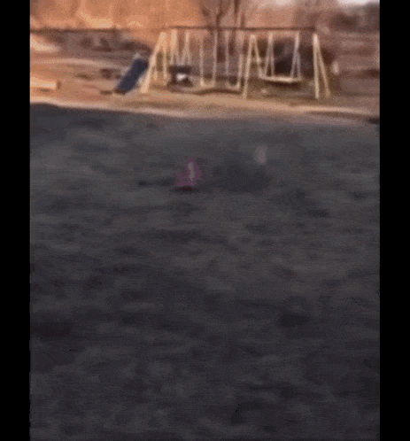 a blurred image of a playground with a few swings and a slide