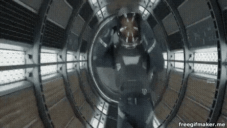 a man in a space suit is walking through a tunnel in a space ship .