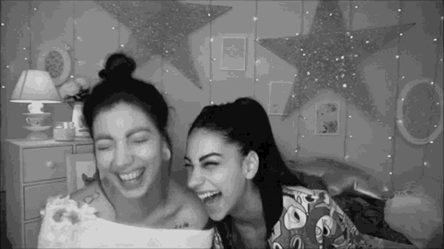 two women are laughing in front of a wall with stars on it