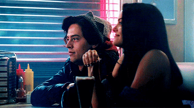 a man and a woman are sitting in a diner looking at each other .