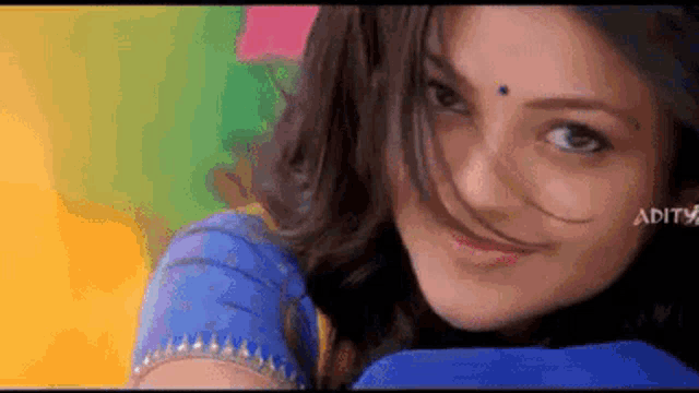 a close up of a woman 's face with her hair blowing in the wind against a colorful background .