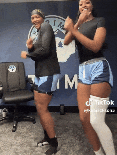 two women are dancing in front of a sign that says tm
