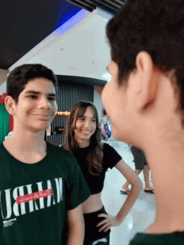 a boy wearing a green t-shirt with the letter j on it is standing next to a girl