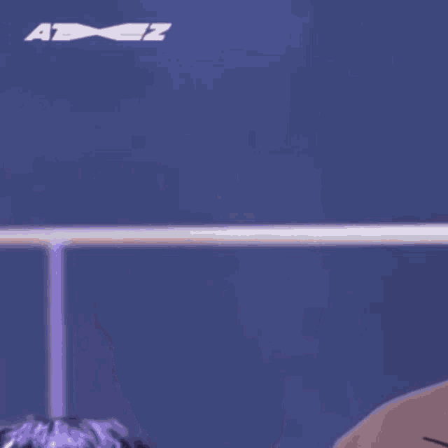 a young man with purple hair is standing in front of a blue wall .