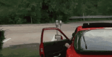 a red car with its door open is driving down a road .