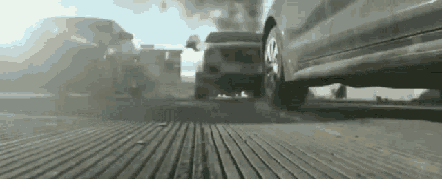 a group of cars are driving down a highway with smoke coming out of the tires .