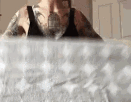 a man with a tattoo on his chest is sitting in a bathtub with a bird cage on his chest .