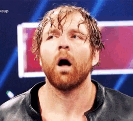 a man with a beard and a leather jacket is making a funny face .