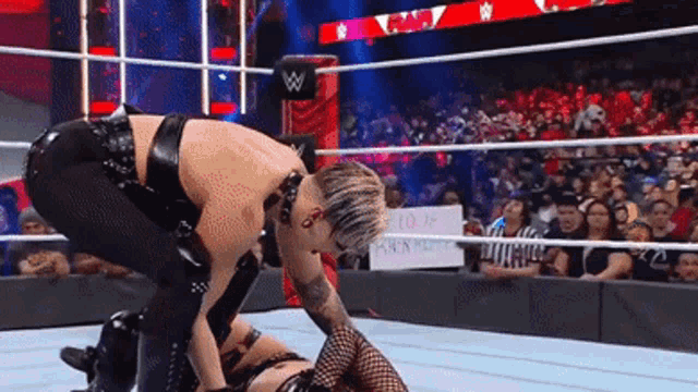 two women are wrestling in a ring with a sign that says ' i love you ' on it