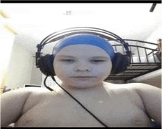 a young boy wearing headphones and a blue swim cap is taking a selfie .