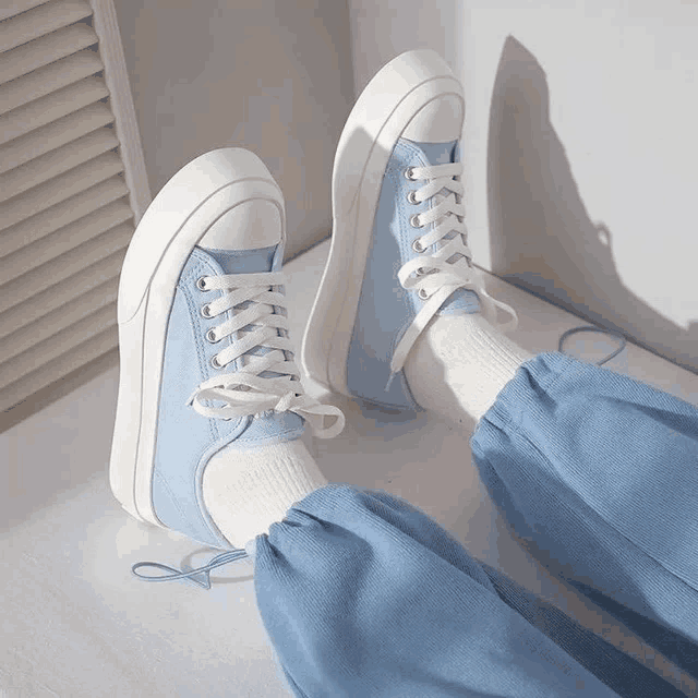 a pair of light blue sneakers with white laces on a person 's feet