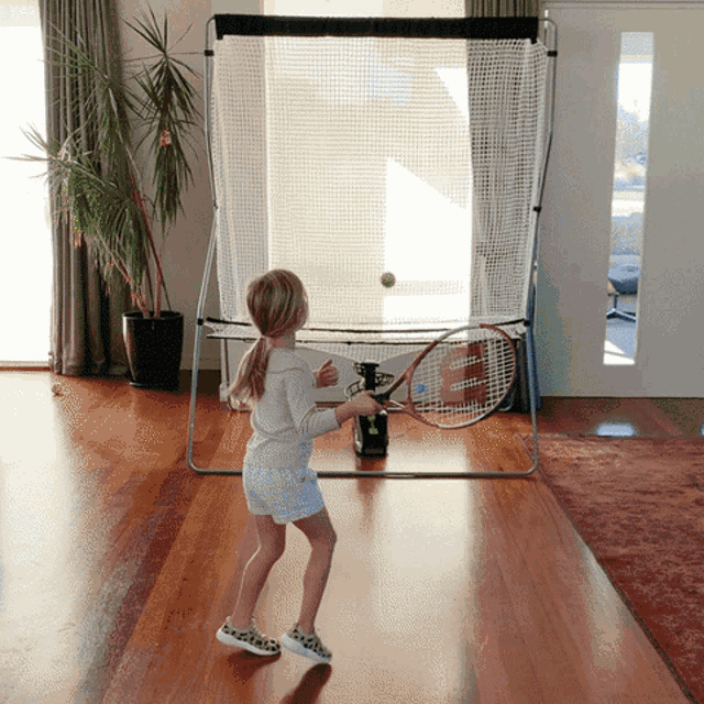 a young girl is playing tennis with a wilson racquet