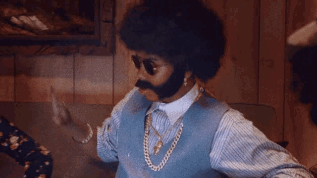 a man with an afro and a beard wearing sunglasses and a necklace