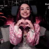 a woman is making a heart shape with her hands and smiling