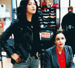 two women standing next to each other in front of a police car