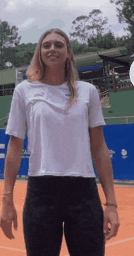 a woman wearing a white t-shirt and black pants is standing on a tennis court