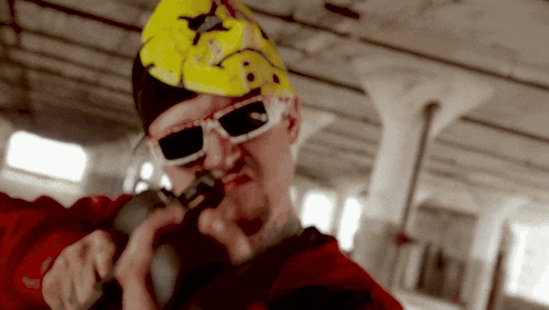 a man wearing a yellow helmet and sunglasses holds a gun