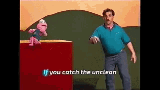 a man is standing next to a stuffed frog on a red box and says `` if you catch the unclean '' .