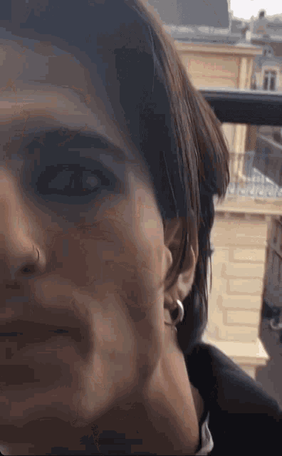 a close up of a person 's face with a nose ring and earrings