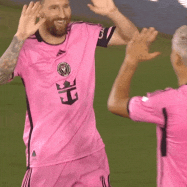 a soccer player wearing a pink shirt with a crown on it