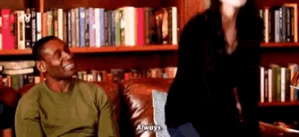 a man and a woman are sitting on a couch in a library .