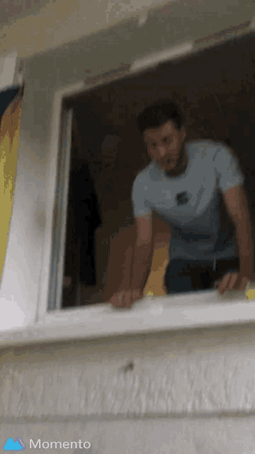 a man is standing in a window with the word momento on the bottom