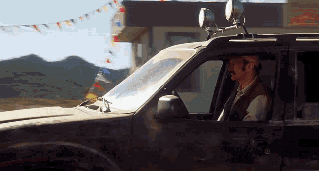 a man is driving a car with lights on top