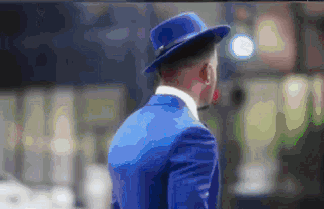 a man in a blue suit and blue hat is walking
