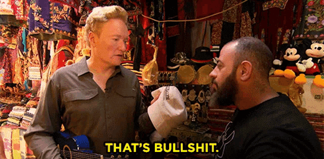 a man holding a guitar says that 's bullshit while talking to another man