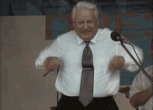 a man in a tie is standing in front of a microphone