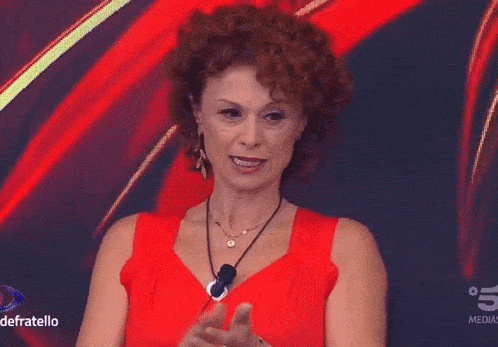 a woman in a red dress stands in front of a screen that says 5 medias