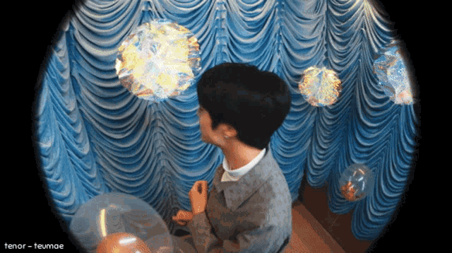 a man blowing soap bubbles in front of a blue curtain with the name tenor-teumae on the bottom