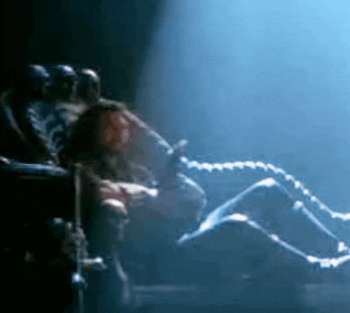a group of people are sitting in chairs in a dark room with a skeleton in the foreground .