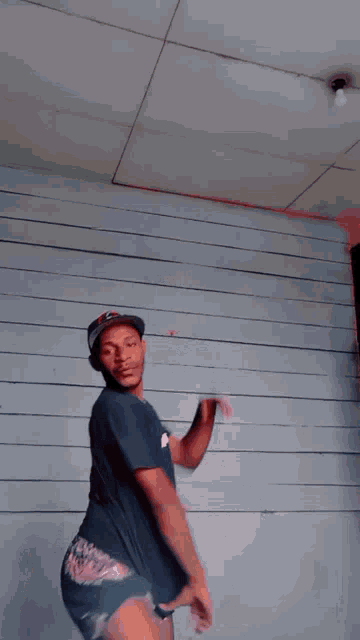 a man wearing a hat and shorts is standing on a wall