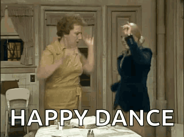 two women are dancing in a kitchen with the words `` happy dance '' written on the screen .