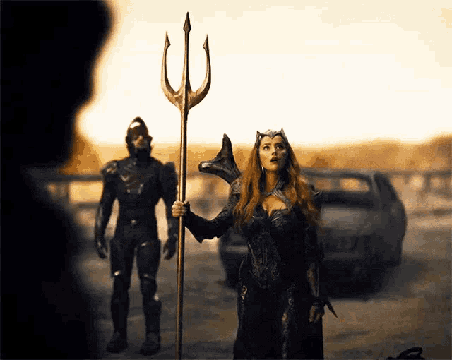 a woman holding a trident stands in front of a man