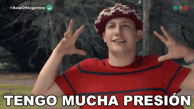 a man wearing a red striped shirt and a hat says " tengo mucha presion "