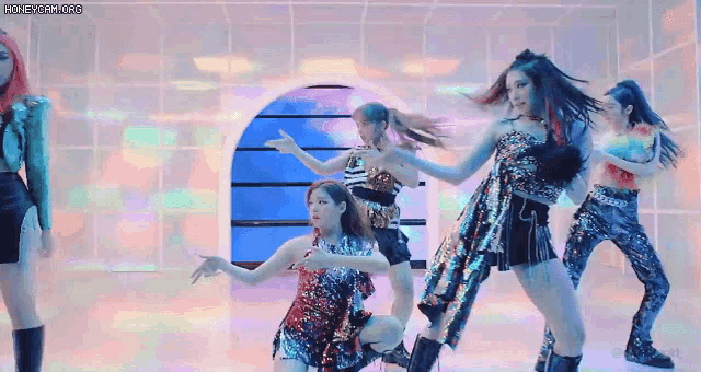 a group of women are dancing in a room with a colorful background .