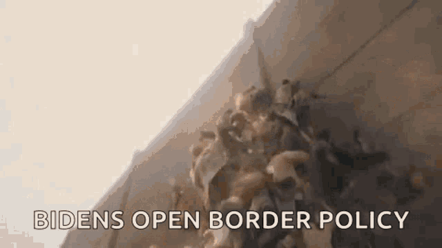 a group of people are standing next to a wall with the words `` bidens open border policy '' written on it .