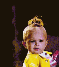 a baby in a yellow jacket is holding a stuffed animal ..