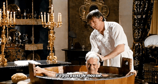 a man washing another man 's head in a wooden tub with the caption y'a pas asses de mousse