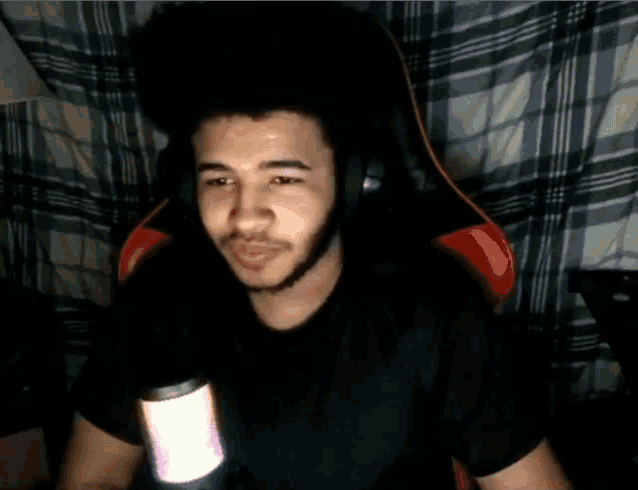 a young man wearing headphones and a black shirt is sitting in front of a microphone