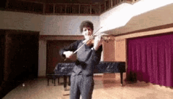 a man is playing a violin on a stage in front of a piano