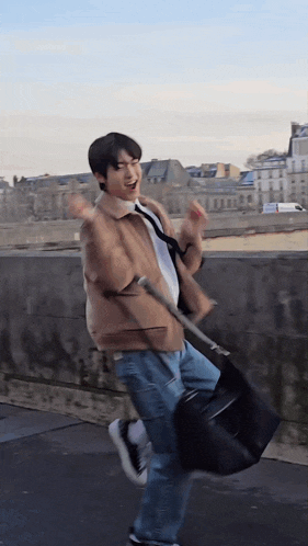 a man in a brown jacket and jeans is holding a black bag
