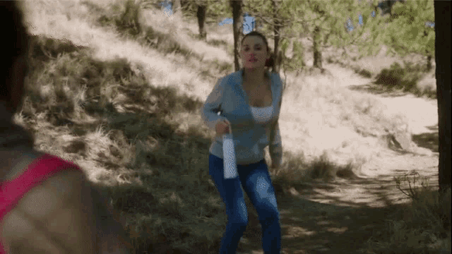 a woman is running down a path in the woods holding a water bottle