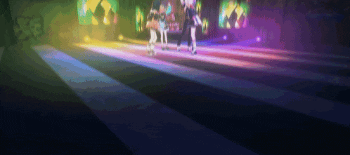 a group of people are dancing on a stage with a rainbow of lights behind them