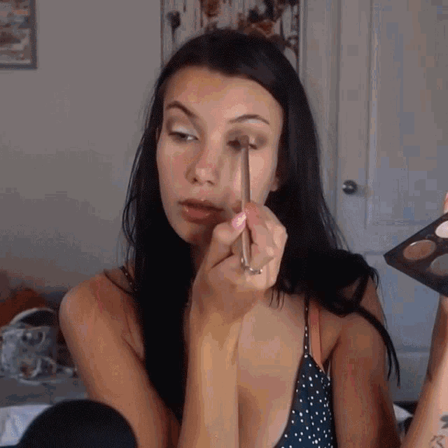 a woman with a tattoo on her arm applying eye shadow