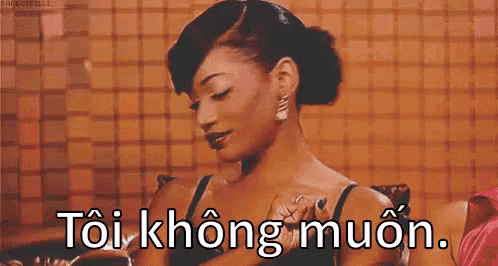 a woman in a black bra is sitting in front of a tiled wall with the words toikhongmuon written on it